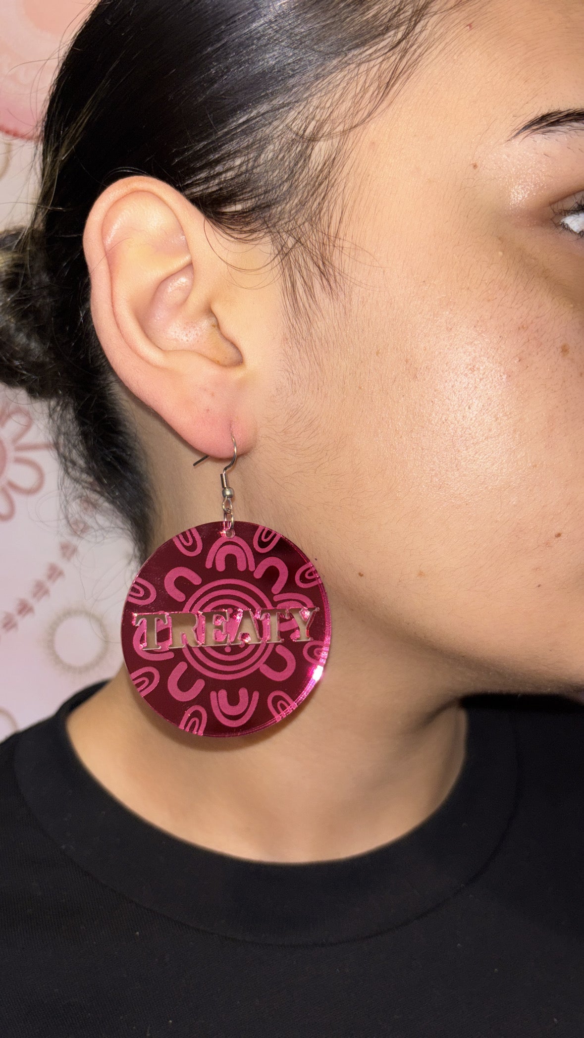 Close-up of a person wearing a red earring with 'TRENDY' text.