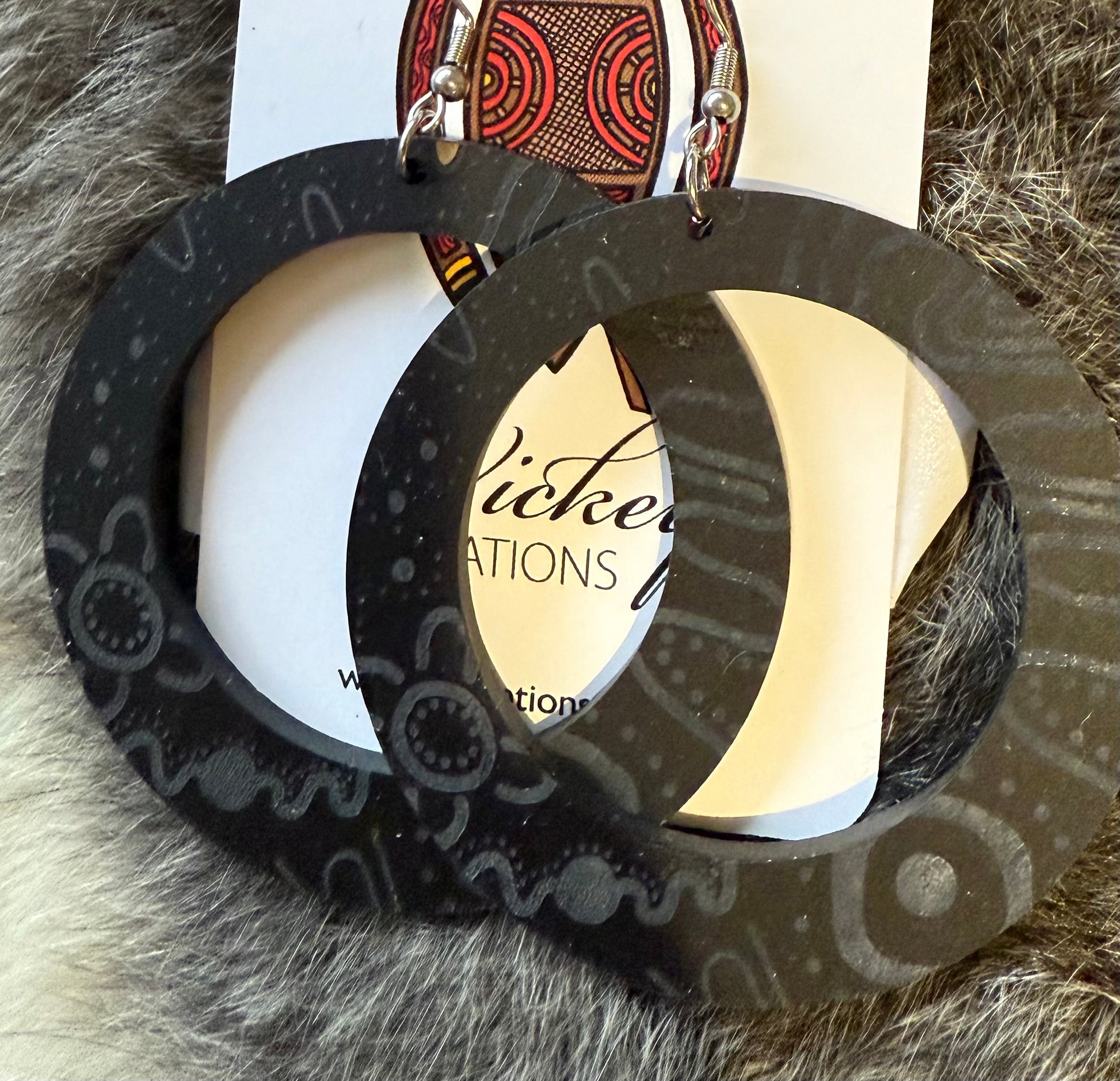 Black hoop earrings on a Wicked Attractions branded card with a textured background