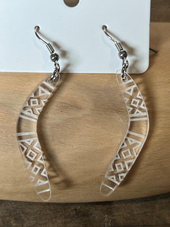Clear acrylic boomerang earrings with stainless steel hooks, displayed on a wooden surface.
